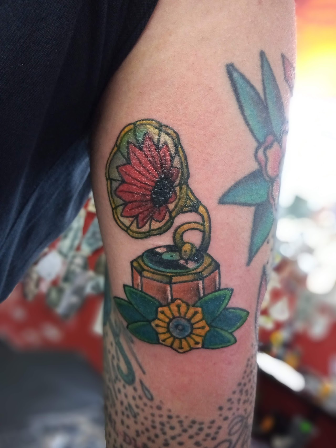 Tatuaje a color de gramófono y flores hecho en Jhon tattoo